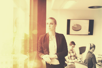 portrait of young business woman at office with team on meeting in background