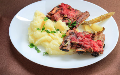 roast pork ribs with tomato sauce crushed potatoes, parsley and pickled cucumbers