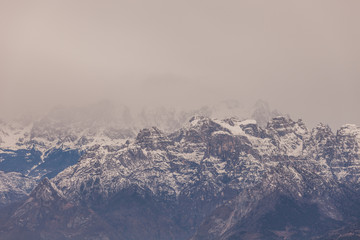 Fototapeta na wymiar Dolomite peaks in the middle of clouds on a gray day, Belluno, Italy