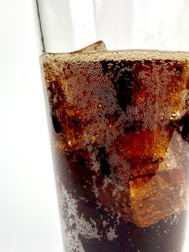 Clear glass of cola over ice against a white background