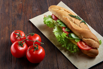 Fresh and tasty sandwich with cheese and vegetables on paper napkin over wooden background, selective focus, top view