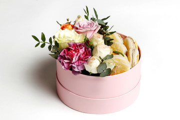 Beautiful bouquet of different flowers with macaroons in a hat box on white background.