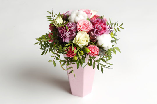 Beautiful bouquet of different flowers in a pink box on white background.
