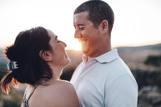Couple embracing each other and smiling at sunset