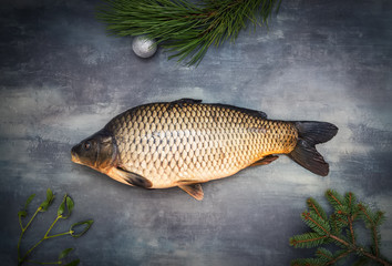 Whole carp with christmas decor on the gray table