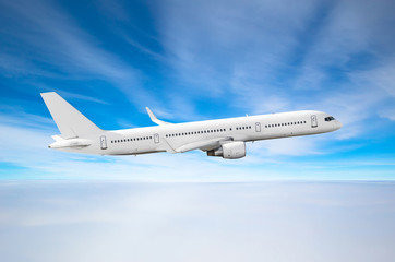 Obraz premium Samolot pasażerski leci wysoko nad zachmurzonymi chmurami i błękitnym niebem.