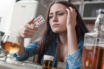 Young woman drug addicted social problems concept sitting looking at pills description