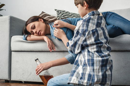 Boy and mother alcoholic social problems concept son trying to wake mom up