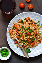 Spaghetti with mussels and green peas in tomato sauce with basil.