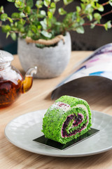 Serving portion of green spinach roll cake with cream cheese and currant filling