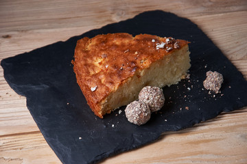 A piece of apple pie with grated chocolate near chocolate truffle candies. Selective focus and small depth of field.