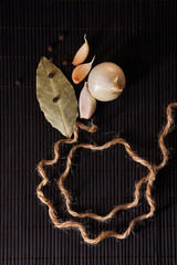 Garlic, onion, bay leaf, black pepper on black table. Food background. Garlics. sliced garlic, garlic clove, garlic bulb.