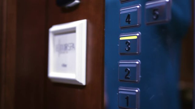 Female hand pushing third floor button on panel into elevator car. Close up woman hand pressing lift button number three on elevator panel