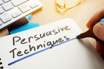 Man writing Persuasive Techniques in a note. - obrazy, fototapety, plakaty