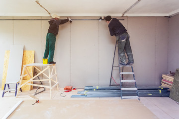 Workers are installing plasterboard drywall for gypsum walls in apartment is under construction, remodeling, renovation, extension, restoration and reconstruction.