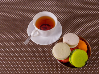 Fototapeta na wymiar cup of tea and a basket of macarons on the table.