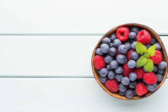 Juicy and fresh blueberries with green mint on rustic blue table.