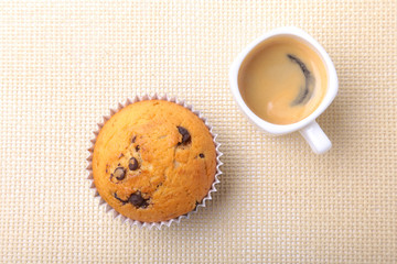 Perfect morning breakfast with Delicious homemade cupcakes with raisins, chocolate chips and espresso coffee in white cup on textile background. Muffins.