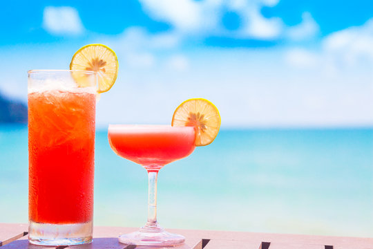 two glasses of fruit cocktail by the beach