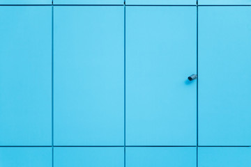 The wall is covered with blue trim panels and security camera. Abstract architectural background.