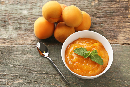 Apricot jam in bowl with spoon on grey wooden table