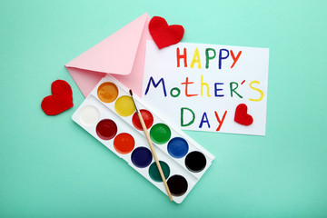 Inscription Happy Mothers Day drawn by watercolor paints with envelope and red hearts