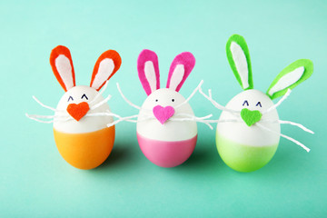 Eggs with funny rabbit faces on mint background