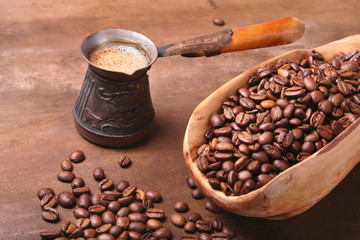 Old wooden scoop with coffee beans, coffee grinder and Cezve on dark stone table.