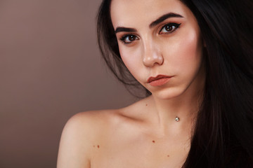 Fototapeta premium Closeup portrait of a beautiful woman. Pretty face of the young adult girl. Fashion model posing at studio. Cosmetology and spa concept.