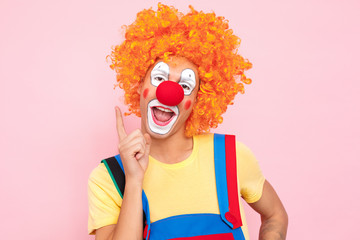 Man in a red wig, overalls and makeup, toothy smile