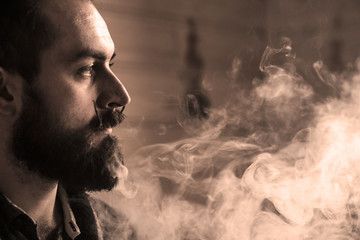 Man with Beard and Mustages Vaping an Electronic Cigarette. Vaper Hipster Smoke Vaporizer and...