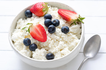 Tvorog, farmers cheese, curd cheese or cottage cheese in white bowl with fresh summer berries