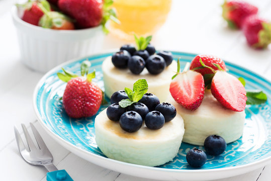 Mini cheesecake or syrniki or cottage cheese pancakes with fresh berries on blue plate