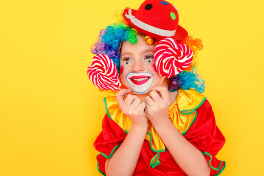 Closeup Portrait Of Little Kid Wearing Clown Suit, Holding Lollipop