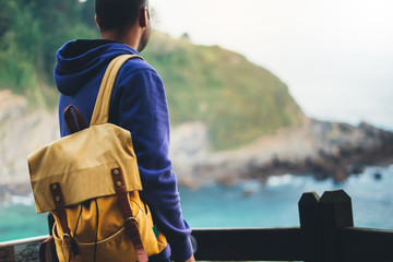 Fototapeta premium traveler relax holiday concept, guy enjoying ocean horizon, panoramic sunrise, sunlight view in trip vacation, hipster hiker tourist with backpack looking on seascape sunset, background