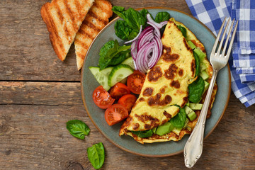 Omelette with avocado, spinach and vegetables with crispy toast from bread. Morning breakfast.
