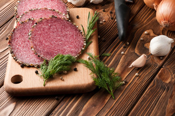 Smoked salami on a old wooden table. Sausages with rosemary , garlic and pepper