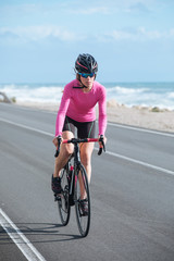 woman cyclist riding a bike on the road close to sea