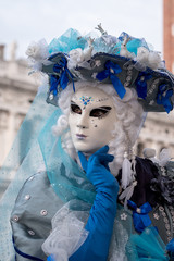 Close up of woman in ornate blue and white costume, hat & mask at St Mark's Square (San Marco) during the Venice Carnival (Carnivale di Venezia)