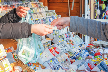 Vendor accepts payment from the tourist for his goods in the market on Old Town Sq. in Prague. Colorful painted eggs belongs among traditional easter decorations since ancient time in Czech Republic.