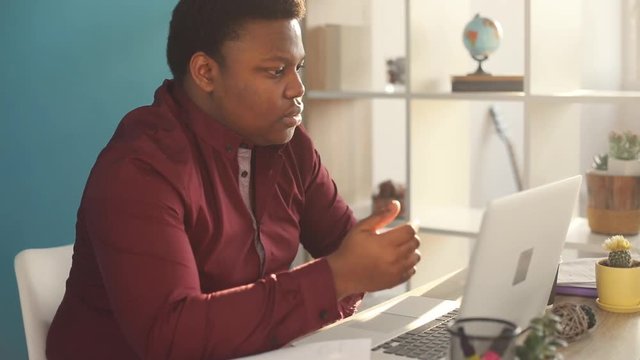 businessman concentrated young african american writing and working on laptop in office sunlight internet face businessman freelance looking portrait serious work slow motion black brainstorming