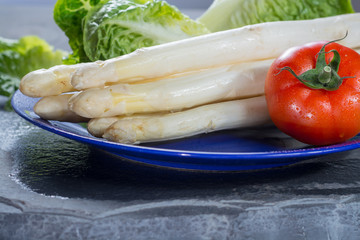 White raw big Dutch asparagus ready to cook, red tomato and green lettuce close up