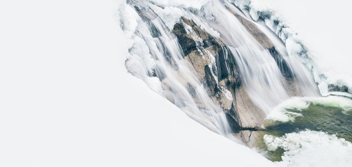 Flowing waterfall with snow and ice in winter