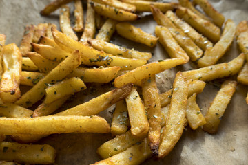 Appetizing fried potatoes located on paper. Close-up.