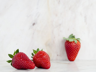 Three ripe strawberries on a marble background