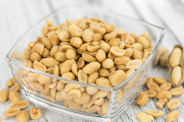 Wooden table with salted and roasted peanuts (close-up shot)