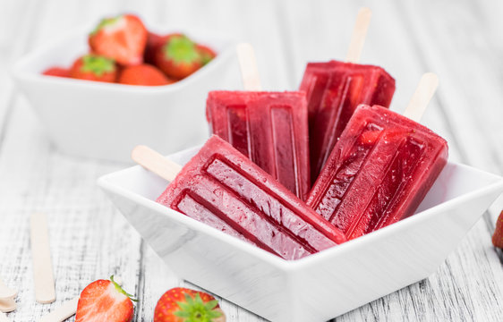 Old wooden table with homemade Strawberry Popsicles