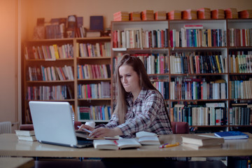 Focused young woman working on laptop in library