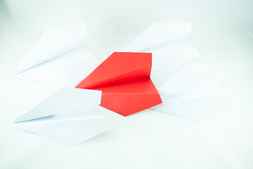 Red paper plane among white ones on a white background, isolated. Concept (idea) of airlines, freedom, leadership, success, and individualism.