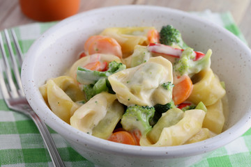 Tortellini with vegetables under cream sauce